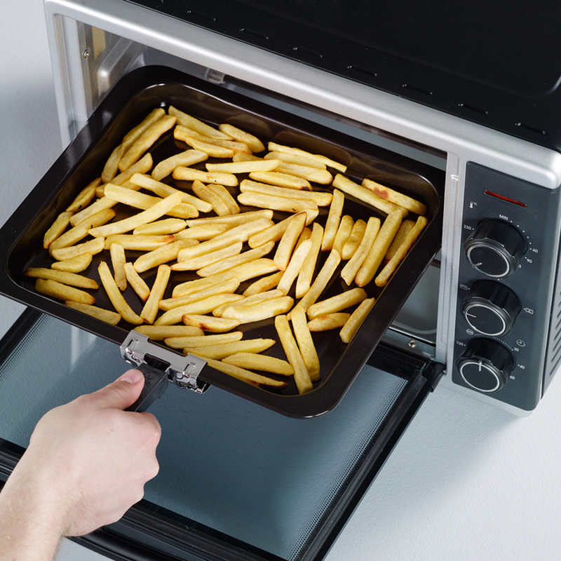 Ofen mit Pommes-Tablett. Hand hält den Tablettgriff. Schwarzer Ofen.