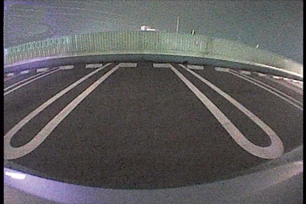 Vogelperspektive eines Parkplatzes mit weißen Linien, die die Stellplätze markieren. Es ist Nacht.
