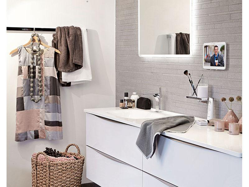 Badezimmer mit Waschbecken, Spiegel und Accessoires. Ein Kleid hängt an einer Stange.