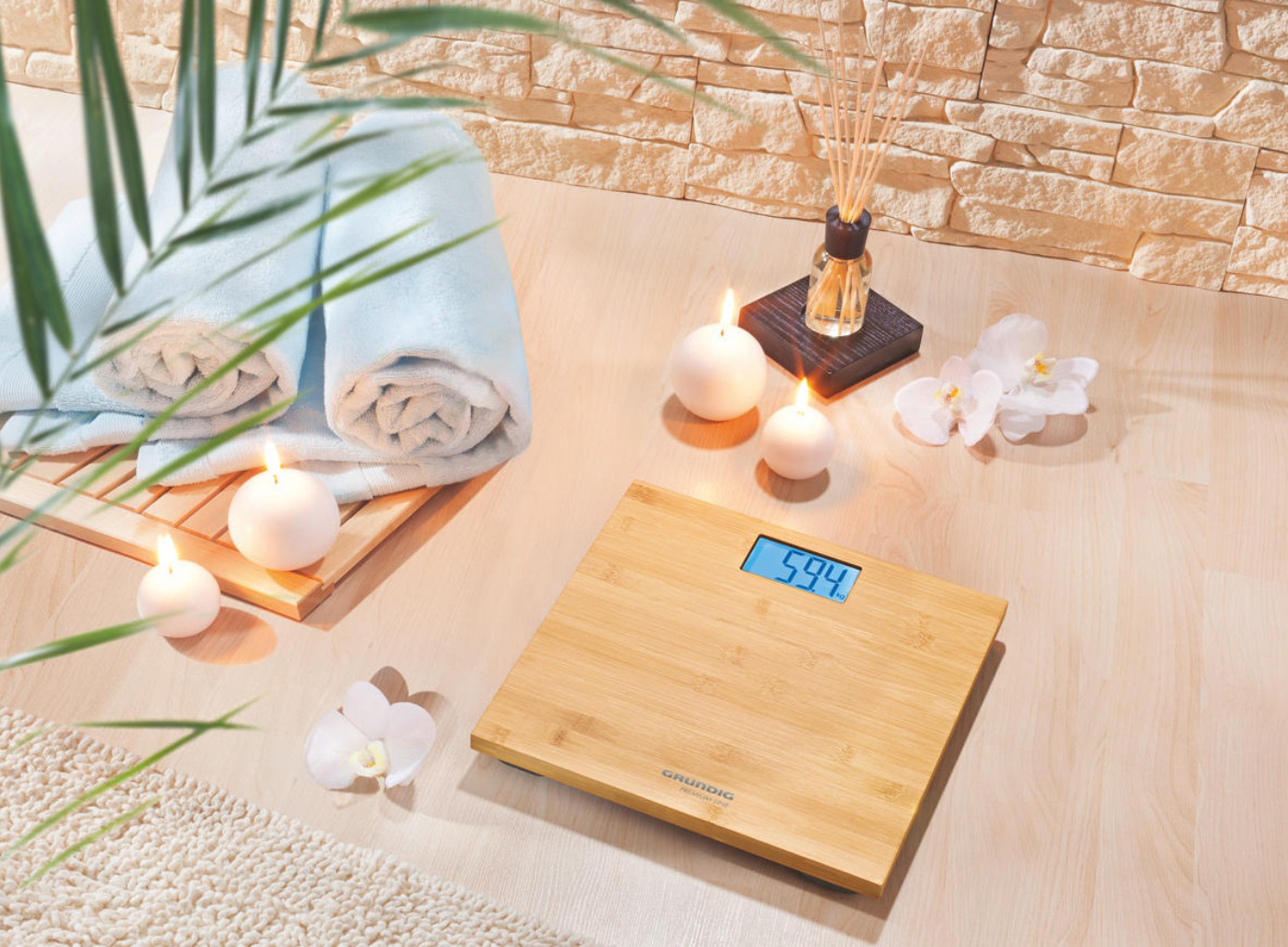 Badezimmer mit Waage. Handtücher, Kerzen, Pflanzen und eine Waage mit 59,4 sind sichtbar.