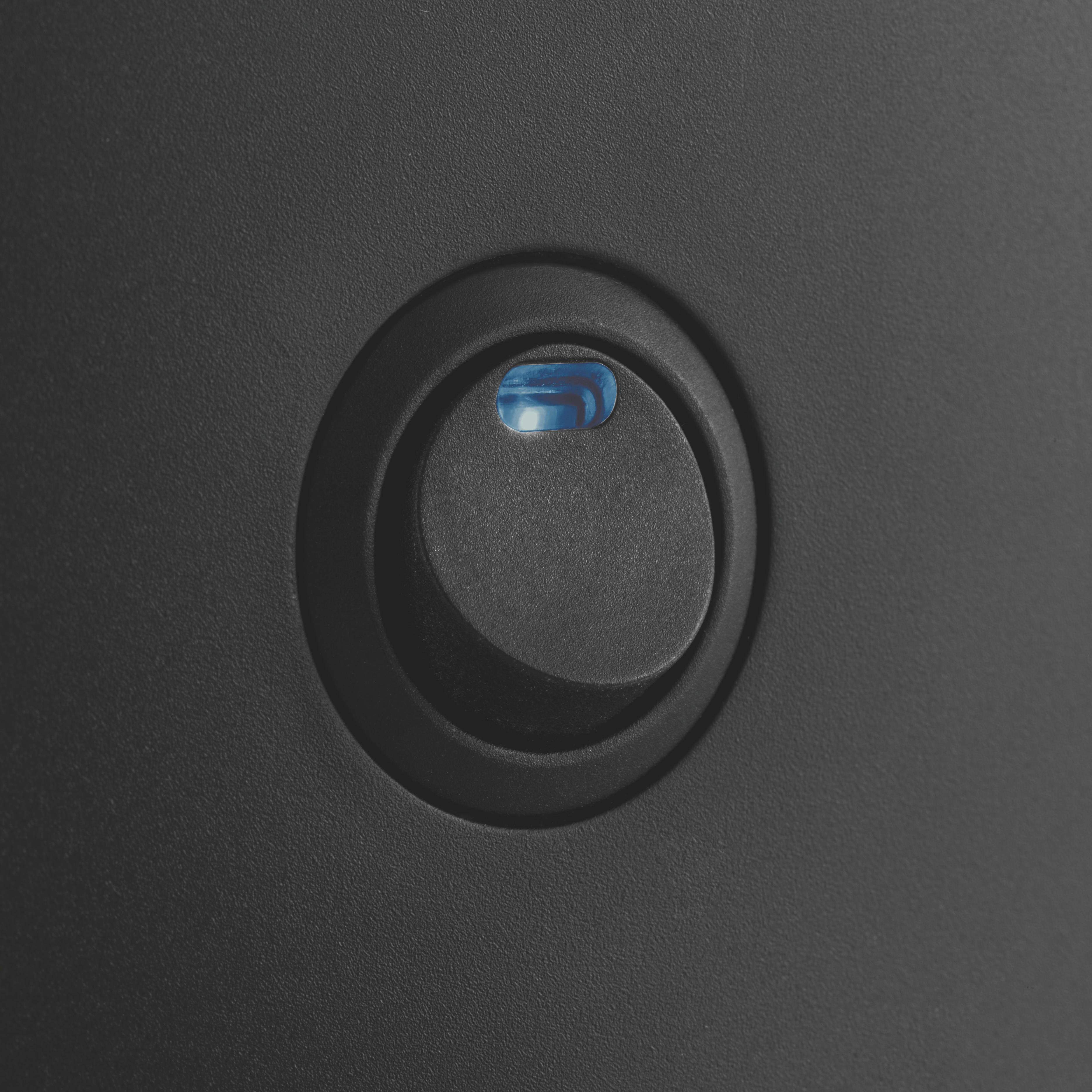 Schwarze Oberfläche mit kreisförmiger Vertiefung und blauem Licht.