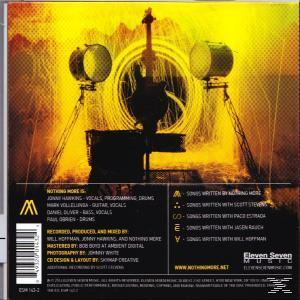 CD-Rückseite mit Bühnenaufbau-Bild. Gelbe und schwarze Farben. Text und Credits sind aufgeführt.