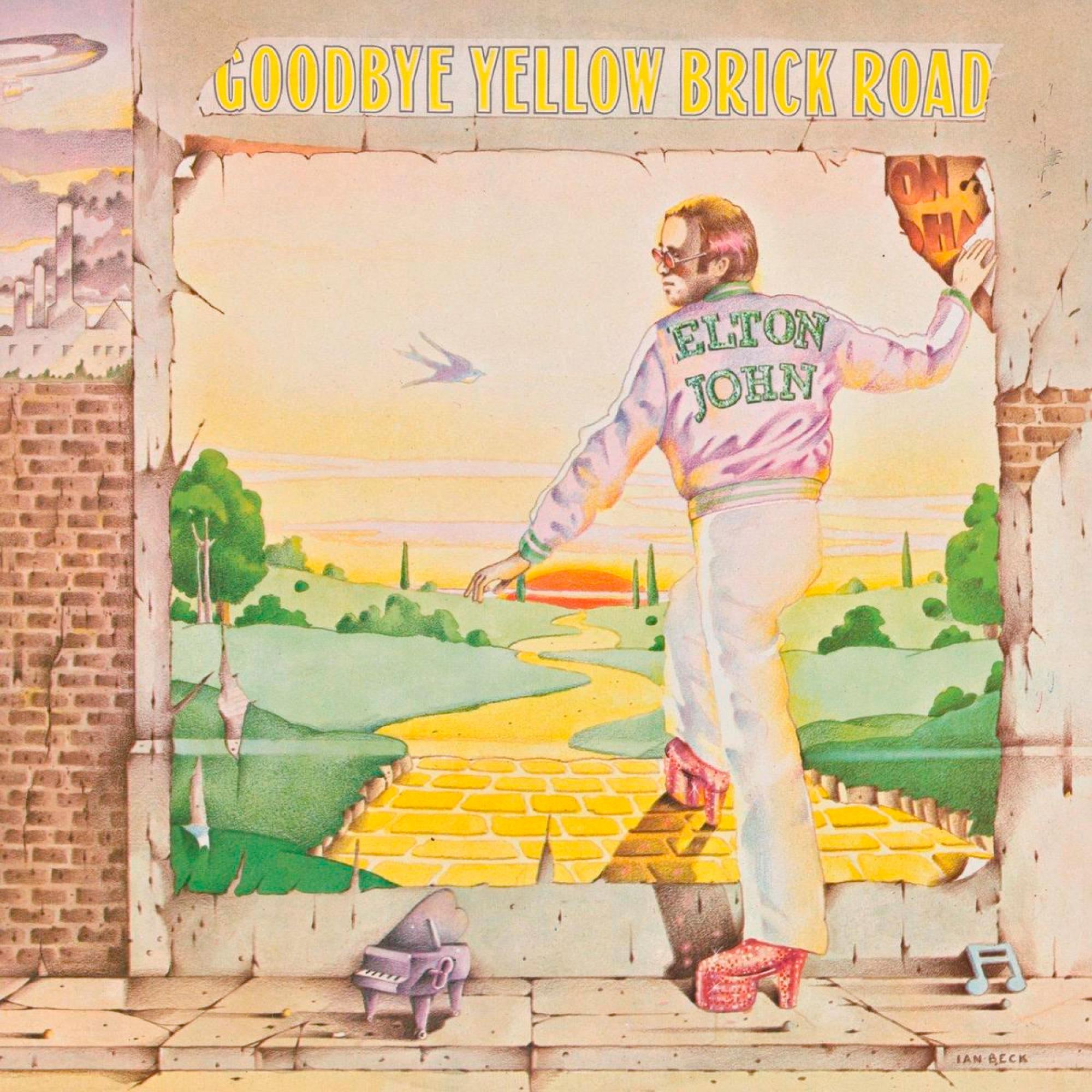 Elton John in weißer Hose und rosa Jacke steht in einer Tür, mit einer gelben Backsteinstraße hinter sich.