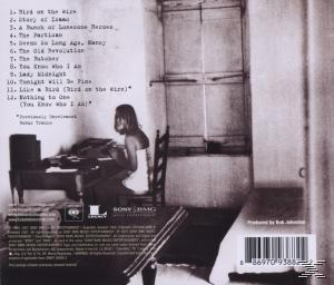 Albumcover. Eine Frau sitzt an einem Tisch und schreibt. Der Hintergrund ist ein Raum mit einem Bett.