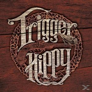 Albumcover: Trigger Hippy. Eine Gewehrillustration in einem kreisförmigen Design auf Holzgrund.