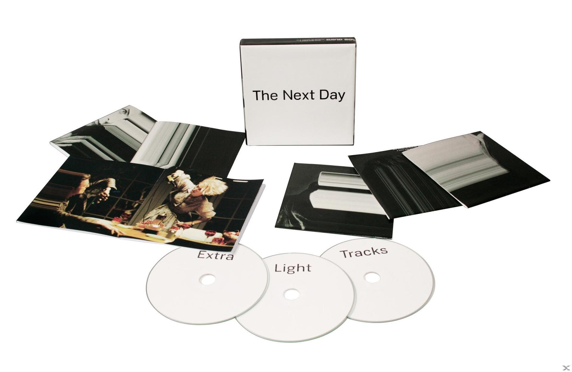 Albumverpackung mit drei CDs, einer Box und Fotos. Der Text 'The Next Day'.