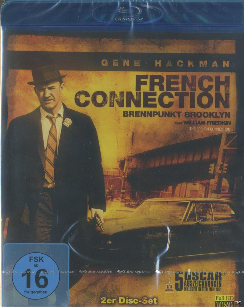 French Connection Filmcover. Gene Hackman in Anzug und Hut, hält eine Pistole. Ein Auto ist hinter ihm, und der Titel ist French Connection.