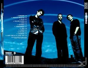 Albumcover, MUSE, 'Showbiz', drei Männer in dunkler Kleidung vor blauem Hintergrund.