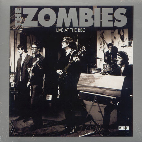 A Zombies együttes a színpadon fekete-fehérben. A zenekar tagjai hangszerükön játszanak.