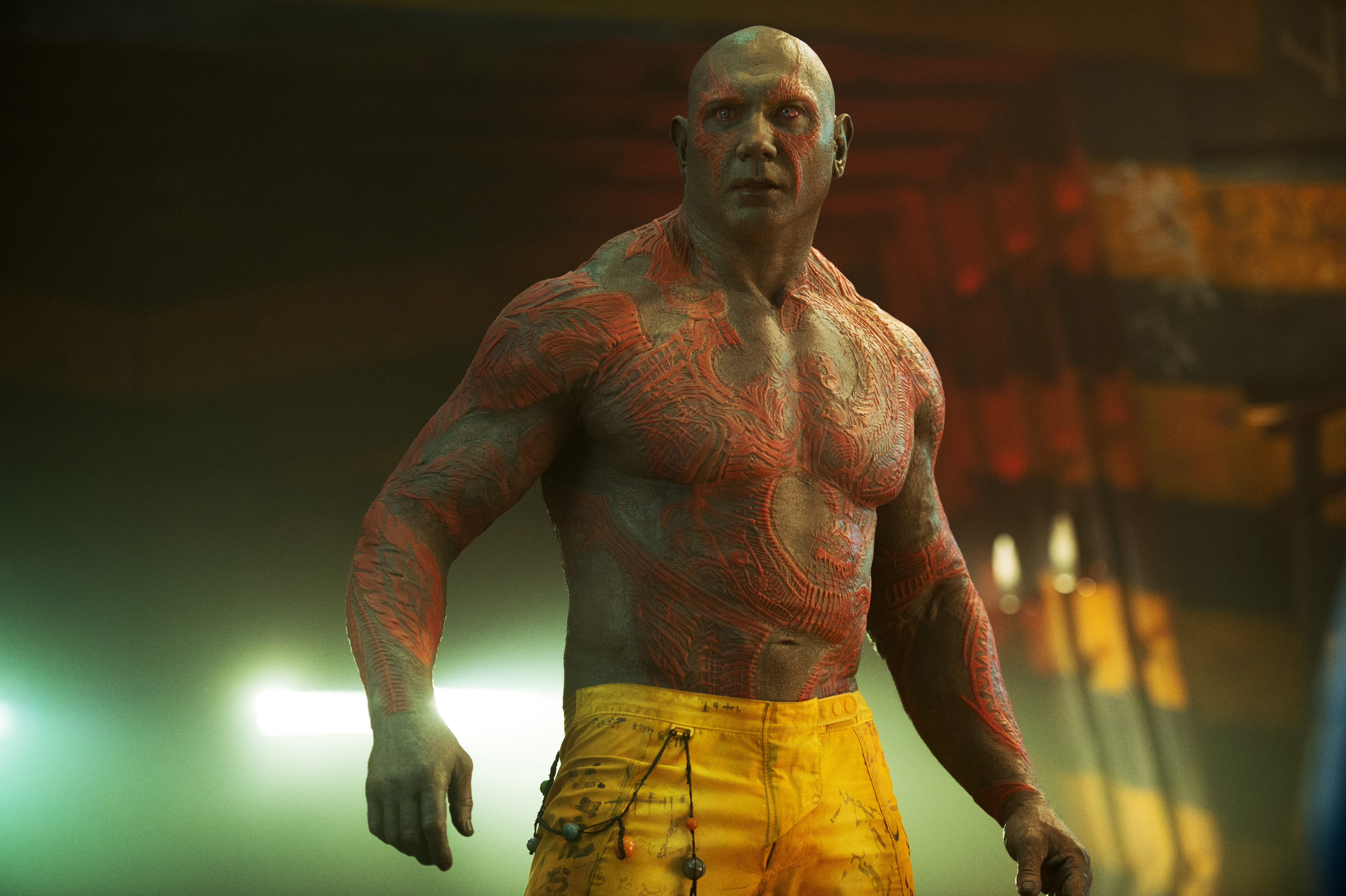 Drax aus Guardians of the Galaxy, ohne Hemd mit roten Körpermarkierungen, gelber Hose und ernstem Blick.