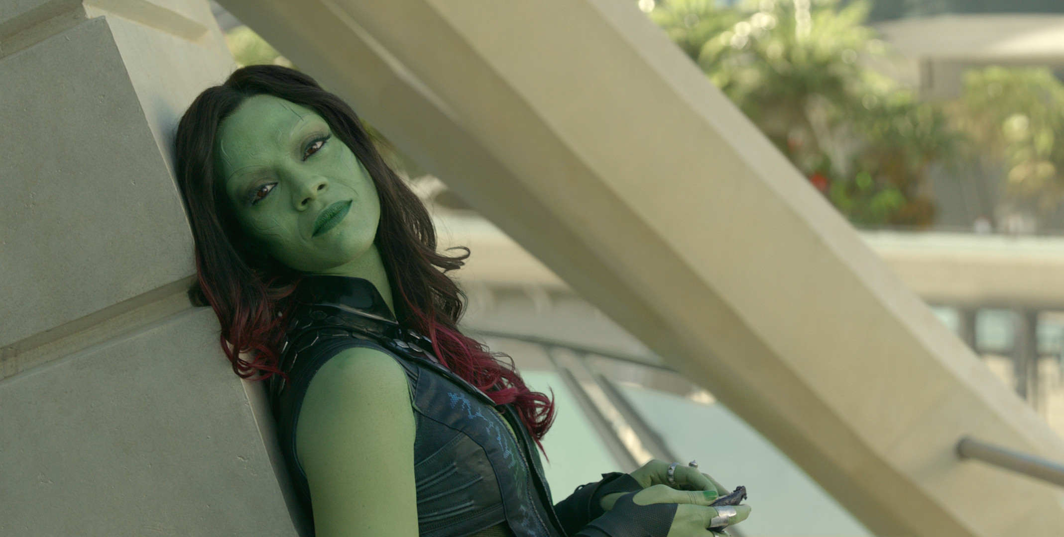 Gamora aus Guardians of the Galaxy lehnt an einer Wand, grüne Haut und rote Haare.