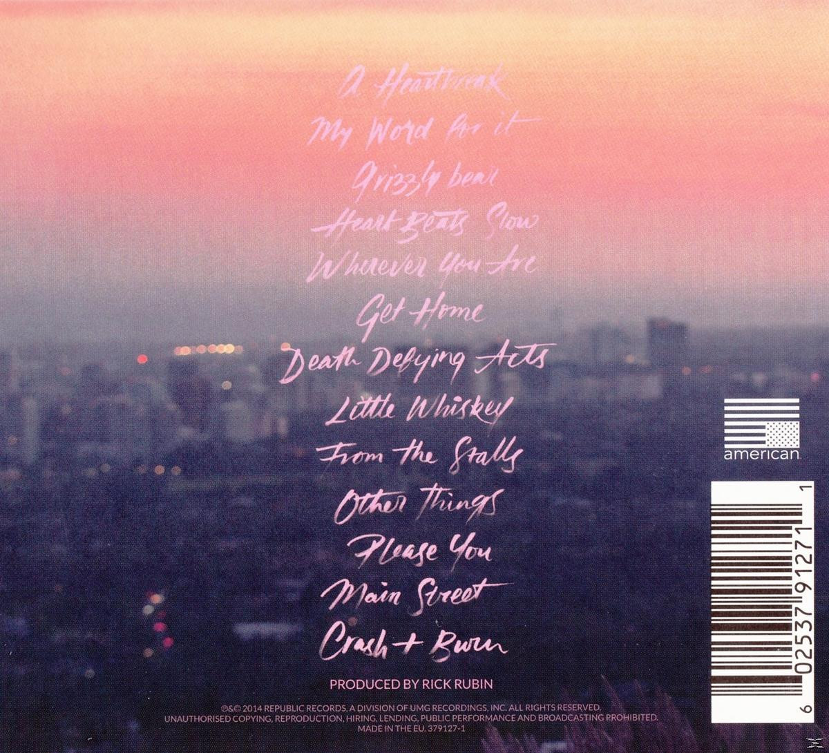 Achterkant van de albumhoes met een stadsgezicht en een lijst met songtitels in cursief. Roze lucht.