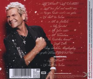 Mann mit blonden Haaren lächelt, trägt eine schwarze Jacke, mit einer CD-Titelliste auf rotem Hintergrund.