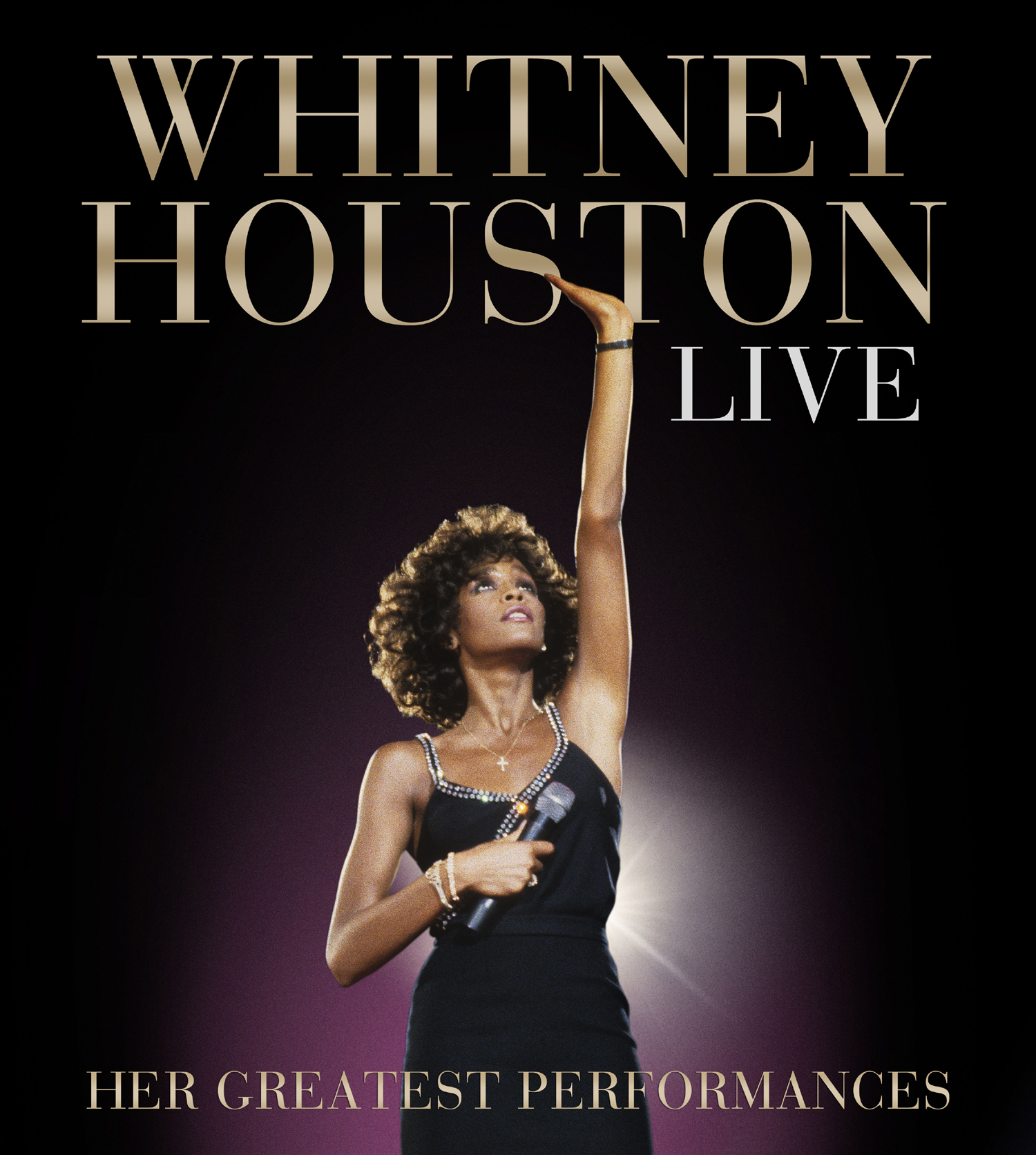 Whitney Houston live bei einer Aufführung. Sie trägt ein schwarzes Kleid und hält ein Mikrofon.