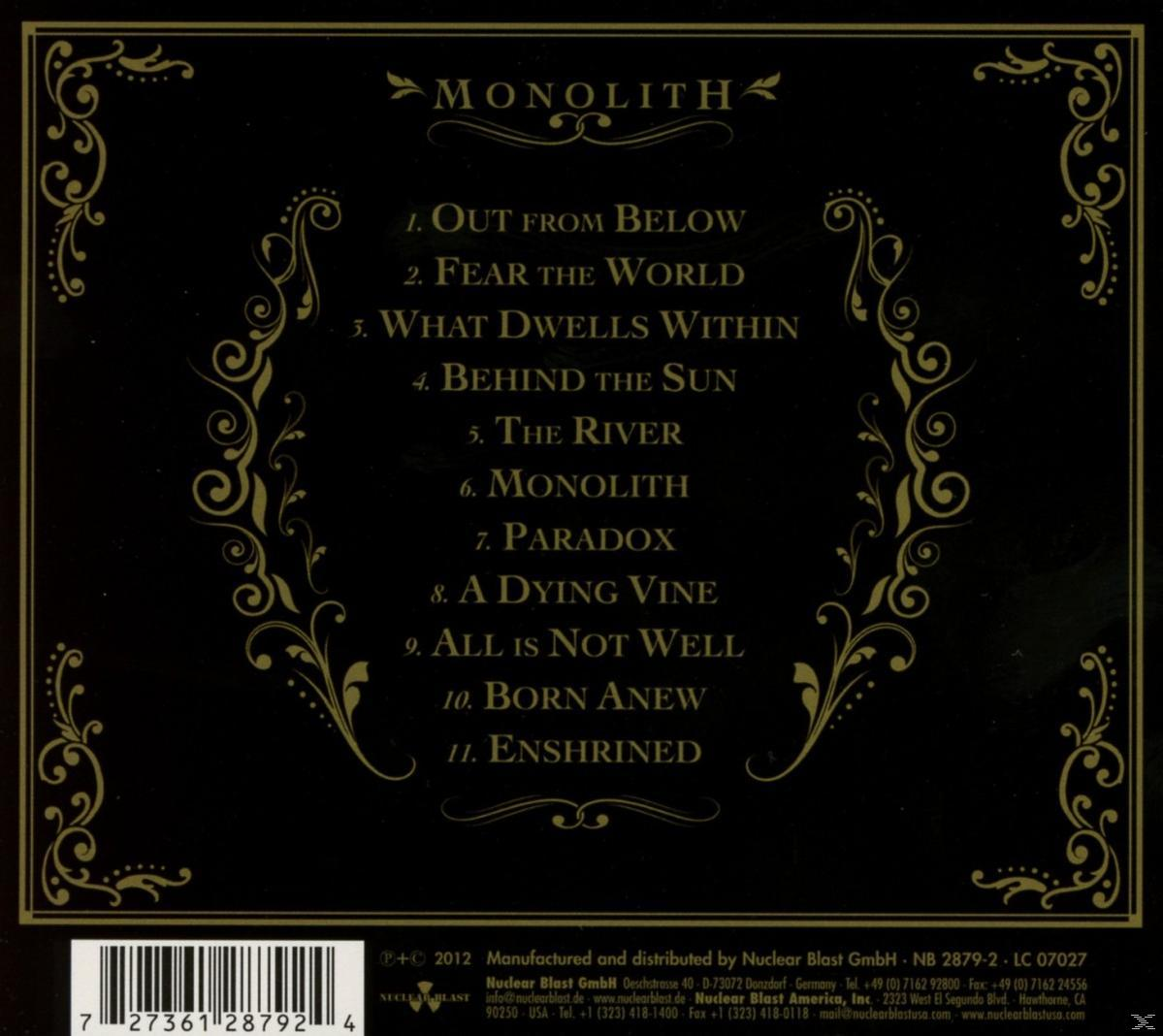 CD-Cover mit Gold- und Schwarz-Design, Text "MONOLITH" und Trackliste. Hintergrund ist dunkel.