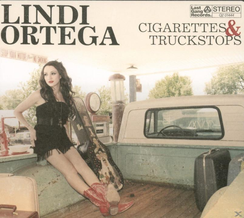 Lindi Ortega Albumcover. Frau in schwarzem Kleid und roten Stiefeln, lehnt an einem Gitarrenkoffer in einem Pickup.