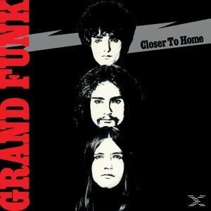 Albumcover: Drei Gesichter übereinander, weiß auf schwarz. Text "Grand Funk" rot links. Titel "Closer To Home".