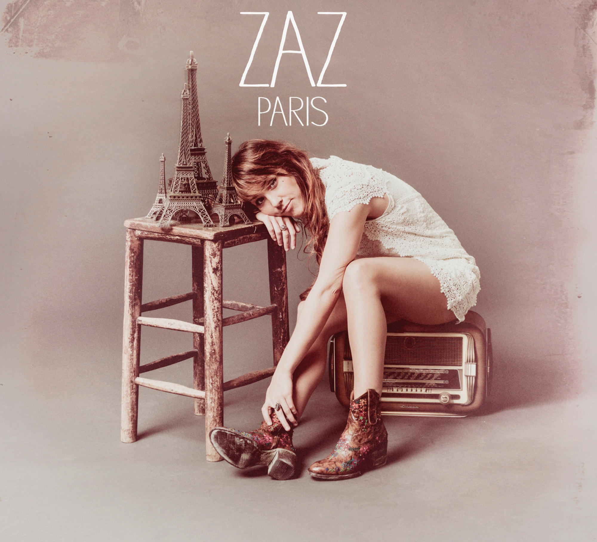 ZAZ-Albumcover, Frau mit Vintage-Radio, Eiffelturm-Replik und Cowboy-Stiefeln.