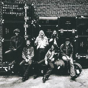 Albumcover mit einer Band, die vor Ausrüstung posiert.