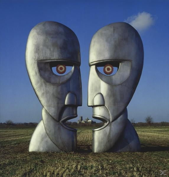Pochette d'album : Deux sculptures de têtes métalliques se font face sur fond de ciel bleu.