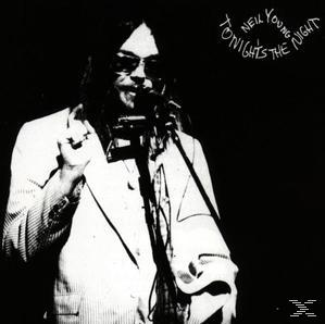 Neil Young mit Mikrofon und Mundharmonika. Er trägt eine Sonnenbrille und einen weißen Anzug.