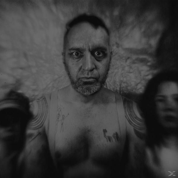 Schwarz-Weiß-Foto eines Mannes mit intensivem Blick, zwei verschwommene Figuren an den Seiten.