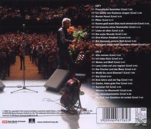 Ein Mann auf der Bühne mit Blumen, Publikum im Hintergrund. CD-Titelliste.