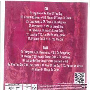 Albumcover mit Titellisten. Rosa Hintergrund, weißer Text. CD- & DVD-Tracklisten und ein dämonisches Bild.