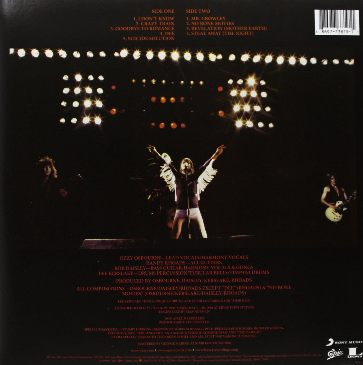 Albumcover mit einer Band, die auf der Bühne auftritt. Der Hintergrund hat helle Lichter.