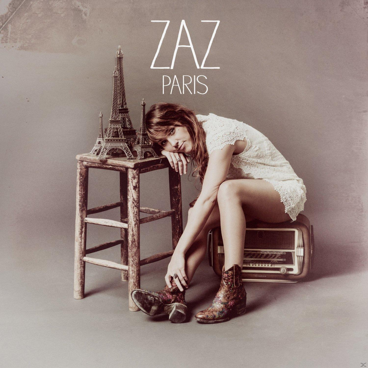 Zaz Paris Albumcover. Frau mit Eiffelturm-Modell, auf Radio sitzend, Stiefel, Text.