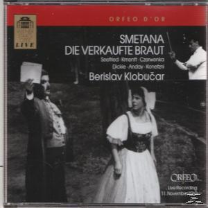 CD-Cover mit einer Bühnenaufführung mit Figuren, einem Dirigenten und dem Titel der Oper.