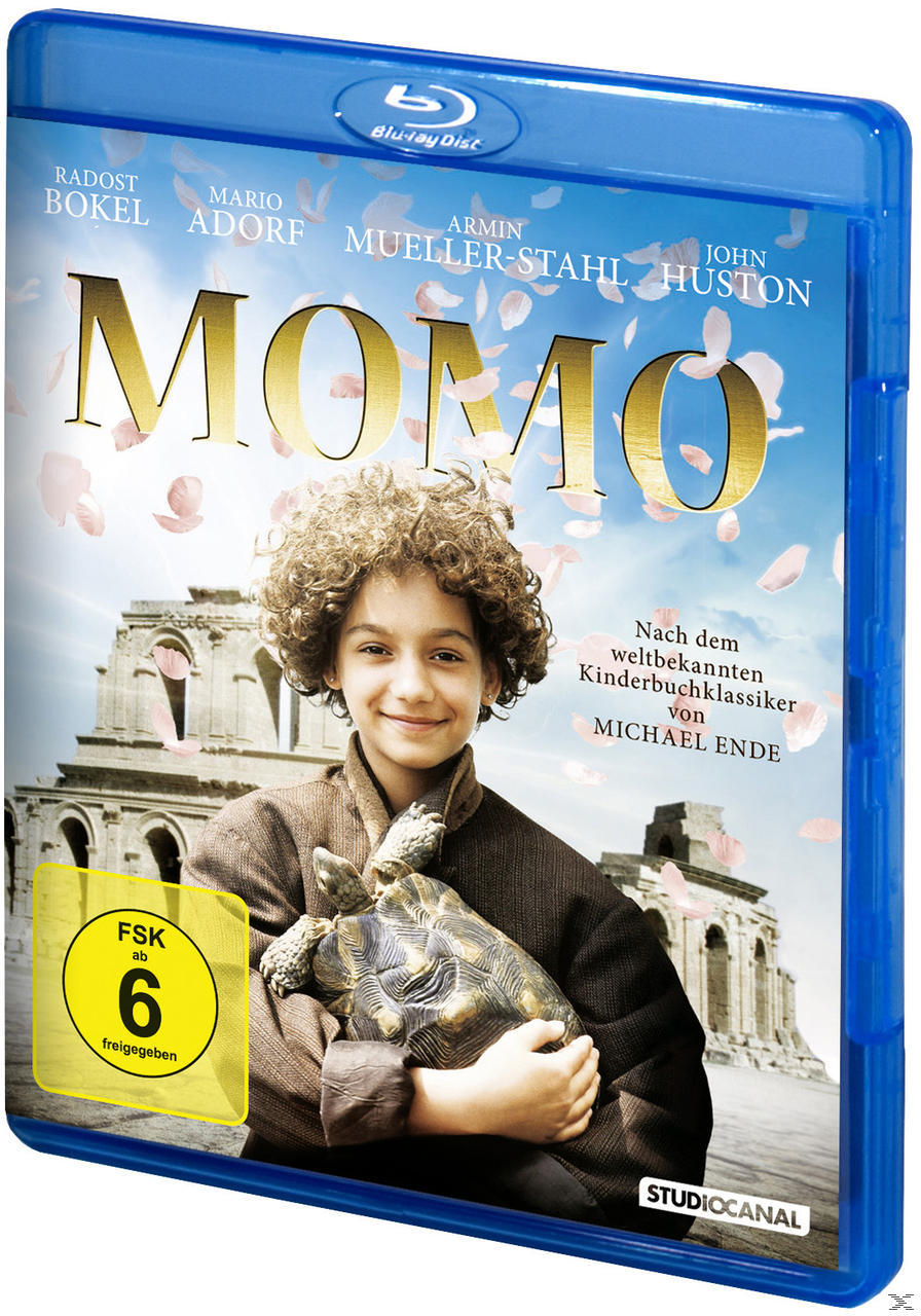 Blaue Blu-ray-Hülle mit Junge und Schildkröte, Filmtitel MOMO, rosa Blumen und Gebäude im Hintergrund.