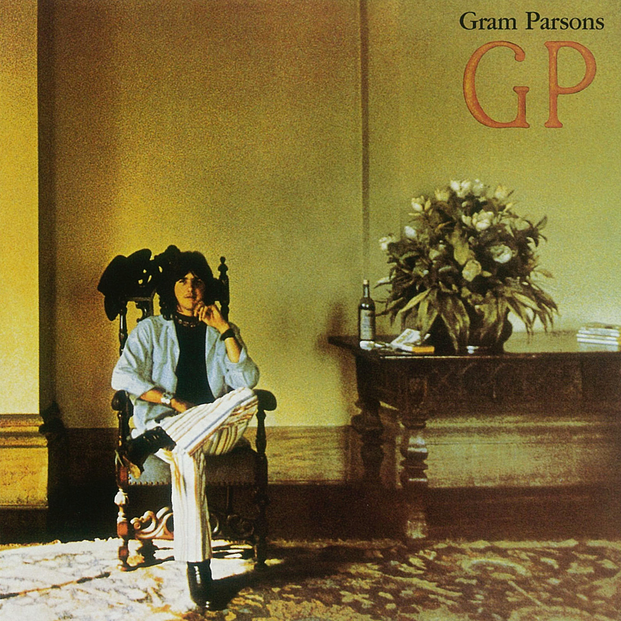 Albumcover von Gram Parsons. Er sitzt in einem Stuhl mit einem Mantel und einem Tisch mit einer Flasche und Blumen.