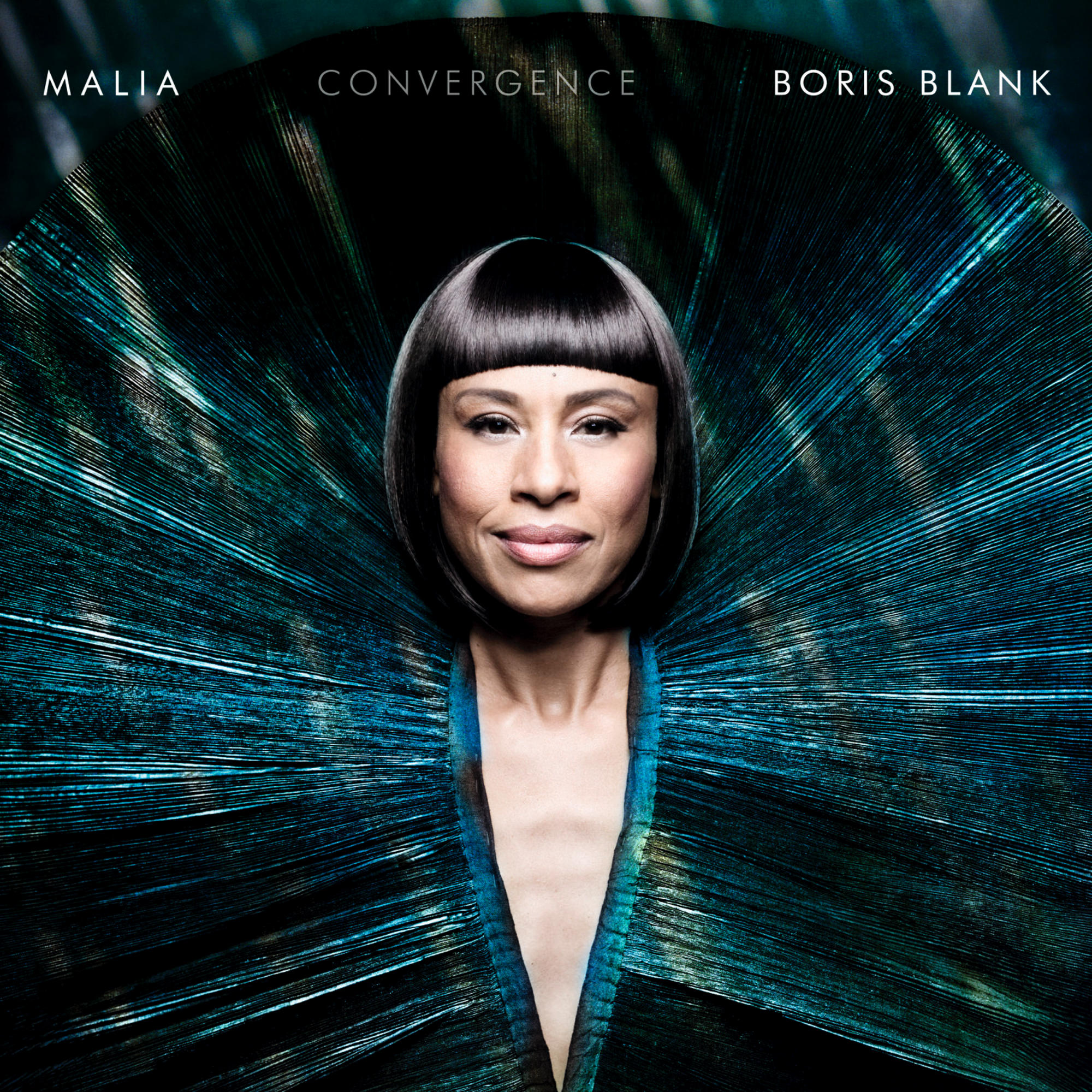 Malia Albumcover, Frau mit dunklem Haar, Pfauenfedern-Design im Hintergrund.