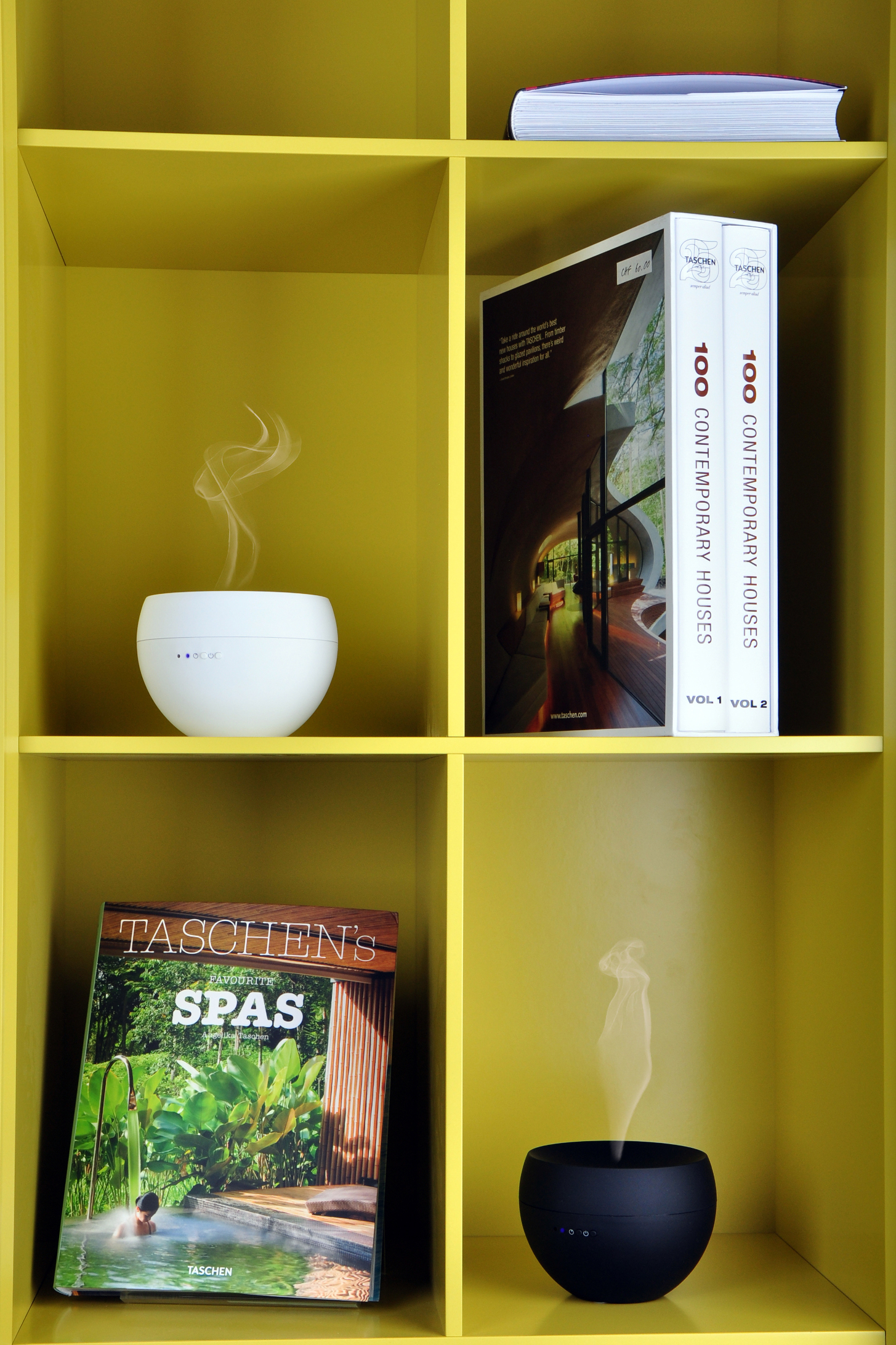 Gelbes Regal mit Büchern und Diffusoren. Dampf kommt aus den Diffusoren.
