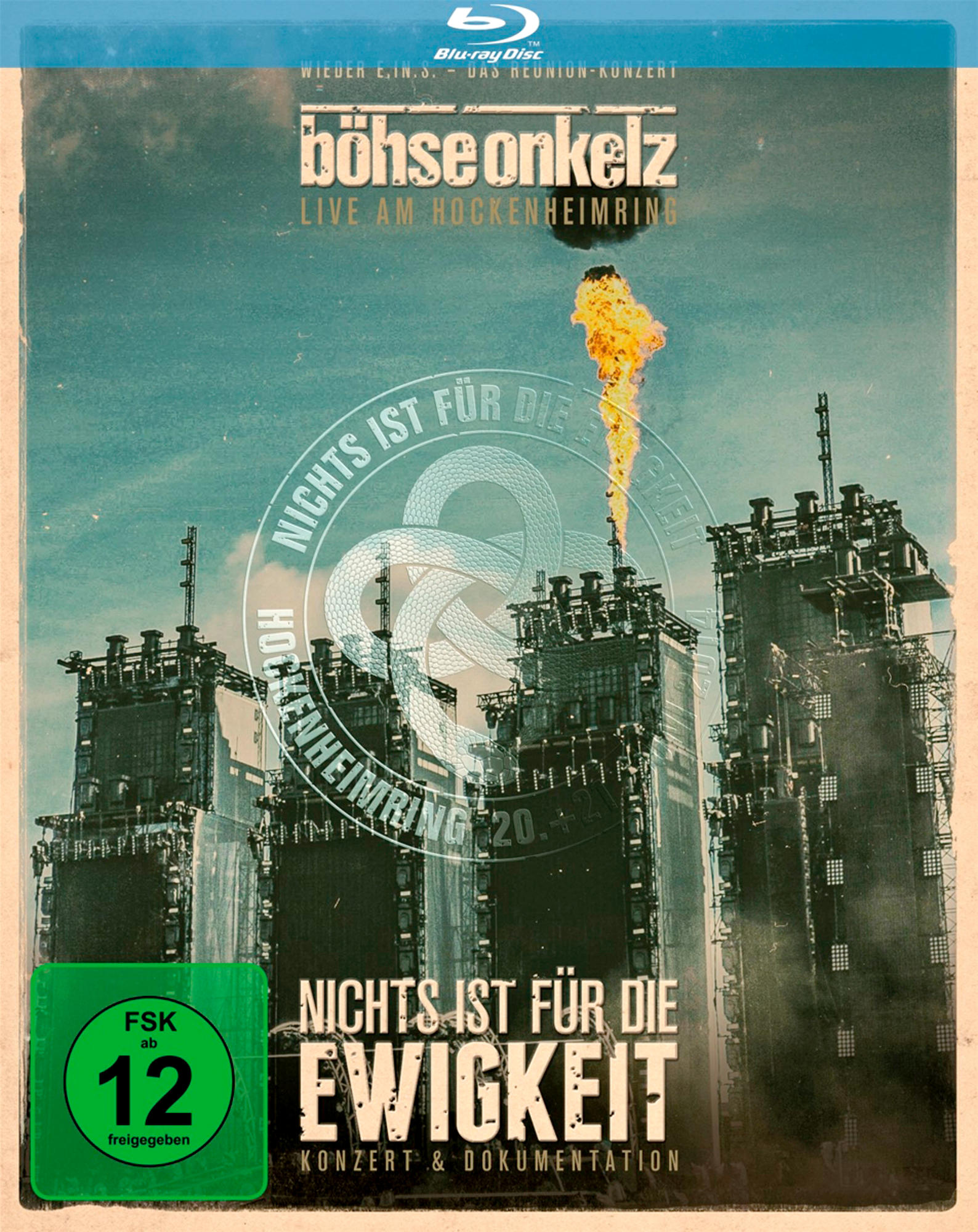 Blu-ray-Cover: hohe Gebäude, Flammen, Text und grüner Altersfreigabeaufkleber.