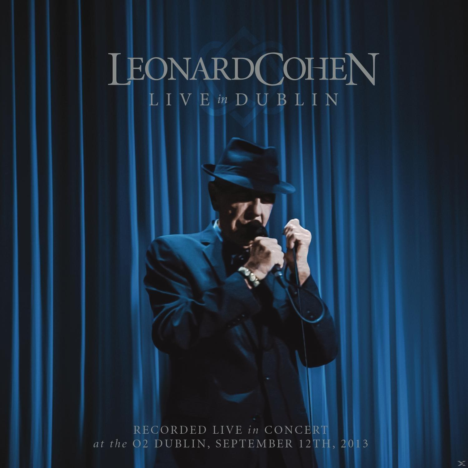 Leonard Cohen dublini koncertjének CD-borítója. Cohen fekete öltönyben, kalapban és mikrofonnal.