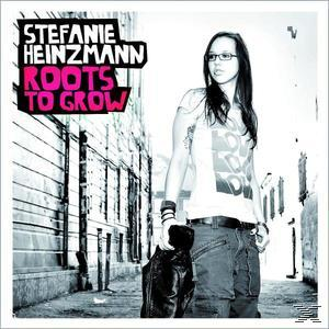 Albumcover: Frau mit Brille, Jacke haltend, auf Straße mit Text stehend.
