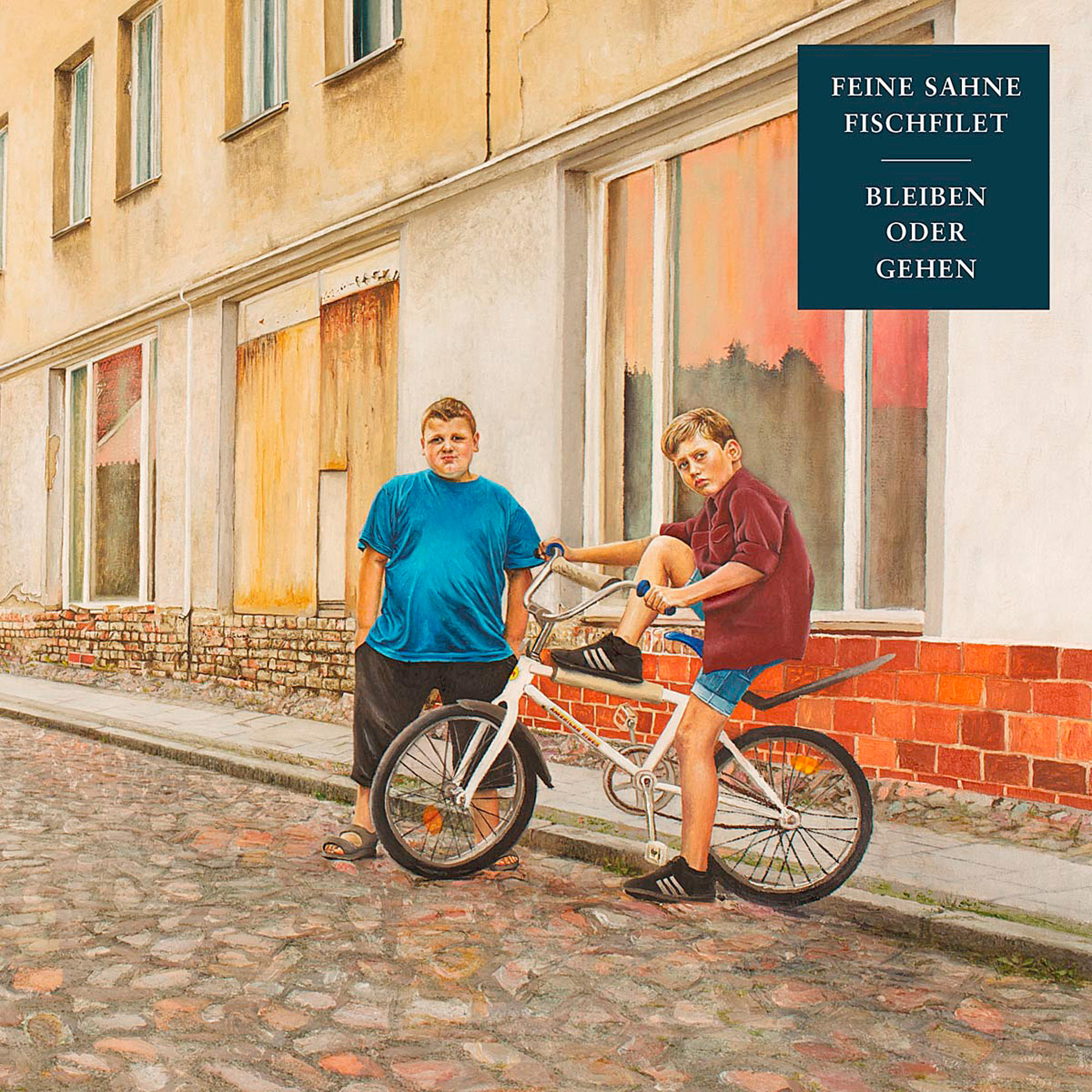 Zwei Jungen mit einem Fahrrad auf der Straße. Einer steht, der andere sitzt darauf.