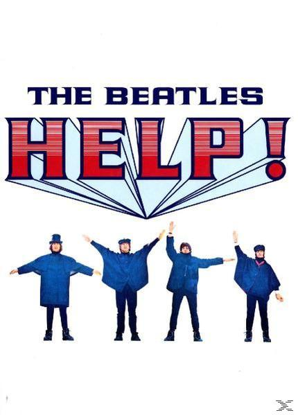 A Beatles kék dzsekiben és nadrágban áll a HELP! felirat előtt.