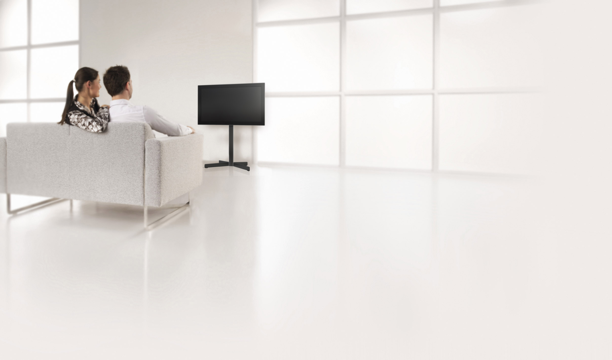 Paar auf Couch, blickend auf leeren Fernseher. Weißer Raum, moderner Stil, helle Beleuchtung.