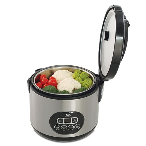 A silver food steamer with the lid open, showing vegetables inside. There are buttons and a screen.