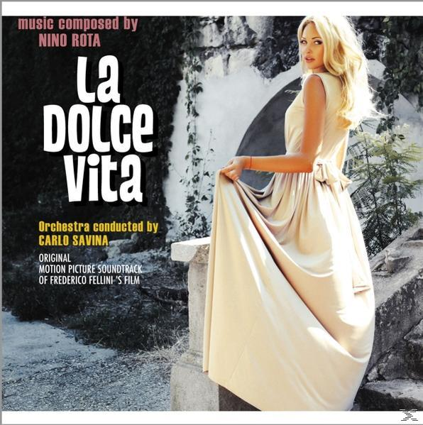 La Dolce Vita Albumcover: Blonde Frau in einem Kleid steht in der Nähe einer Steinmauer.
