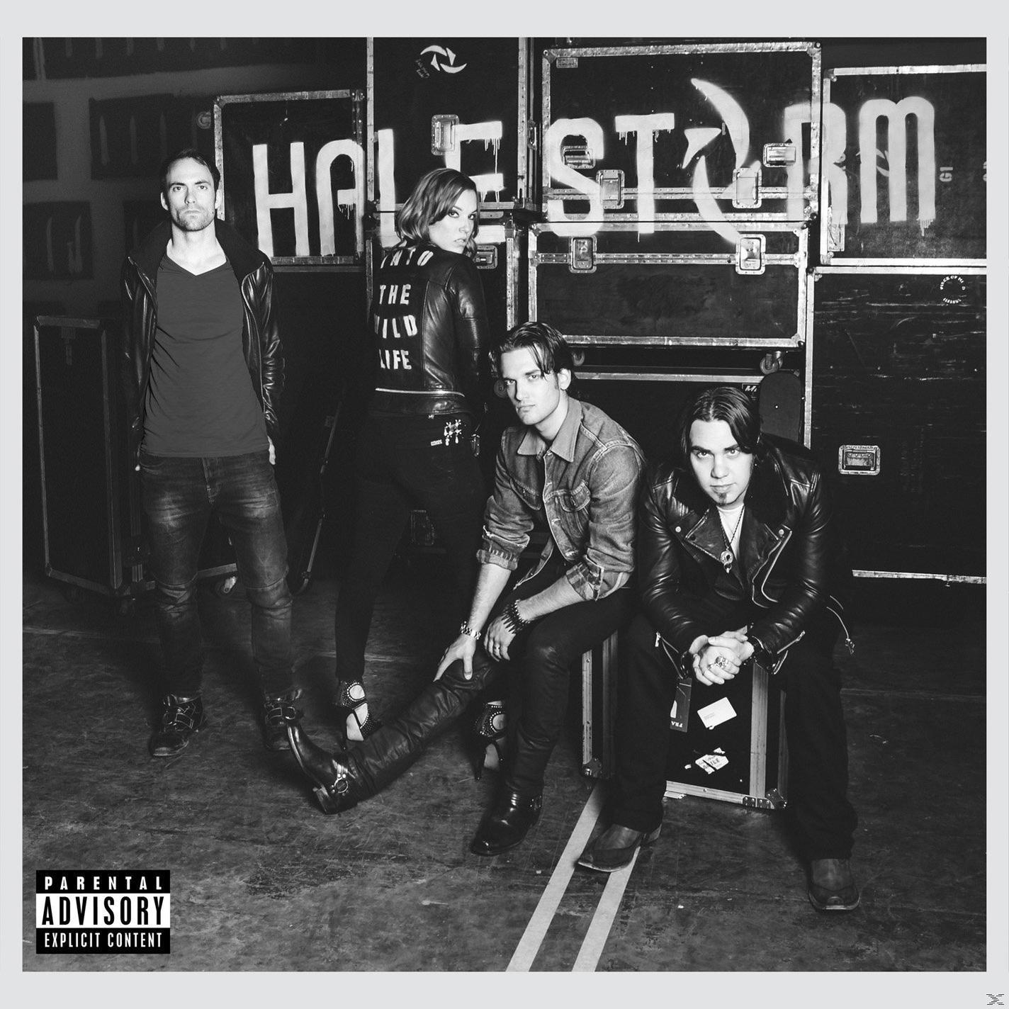 Band Halestorm posiert vor Gerätecases. Das Parental Advisory-Logo befindet sich unten links.