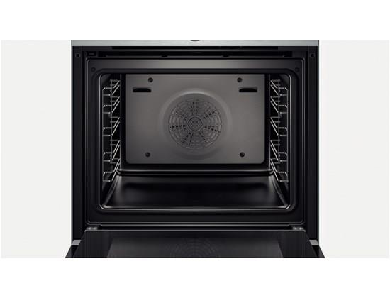 Intérieur d'un four ouvert. Le four est noir, avec des grilles métalliques et un ventilateur.