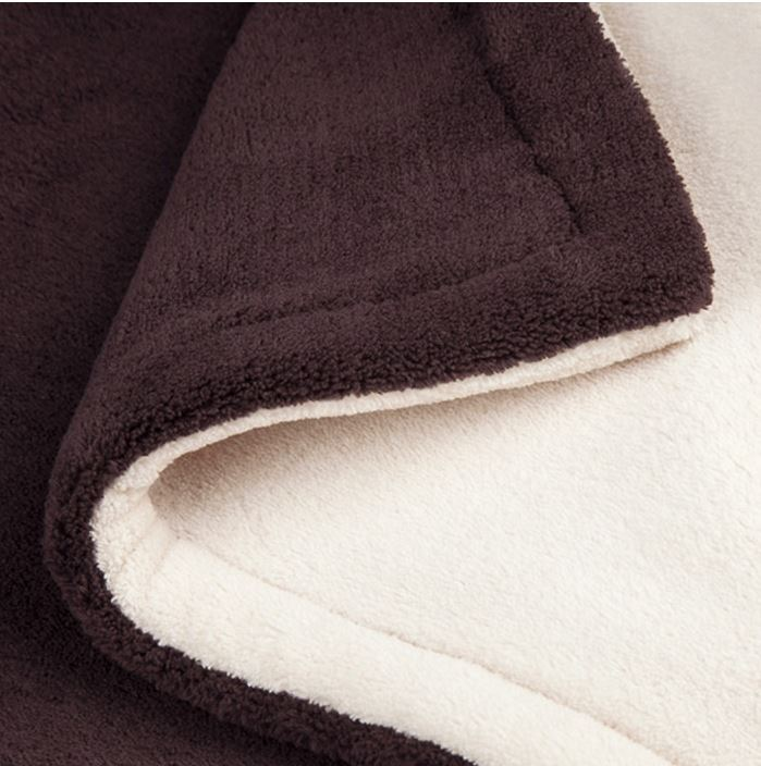 Gros plan sur une couverture marron et crème, pliée.