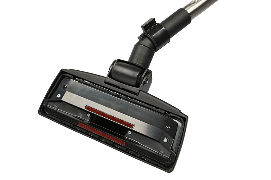 Vacuum cleaner head. Black with red brushes, and a metal plate. White background.