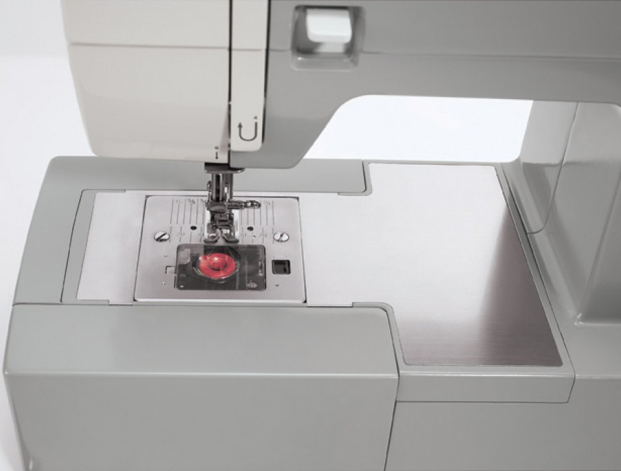 Close-up of a sewing machine, silver plate, gray body, white background.