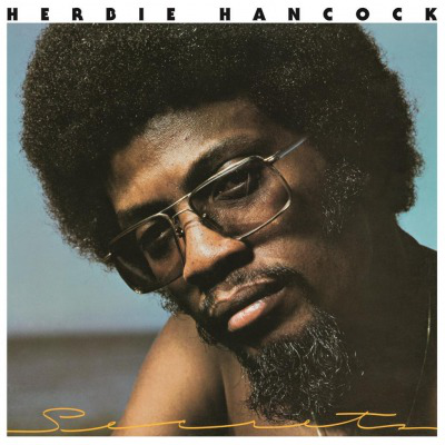 Herbie Hancock album borítója. Férfi szemüveggel, afroval és szakállal. Világoskék és barna háttér.