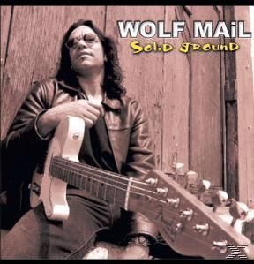Mann mit Brille hält Gitarre, sitzt. Text lautet 'WOLF MAIL SOLID GROUND'.